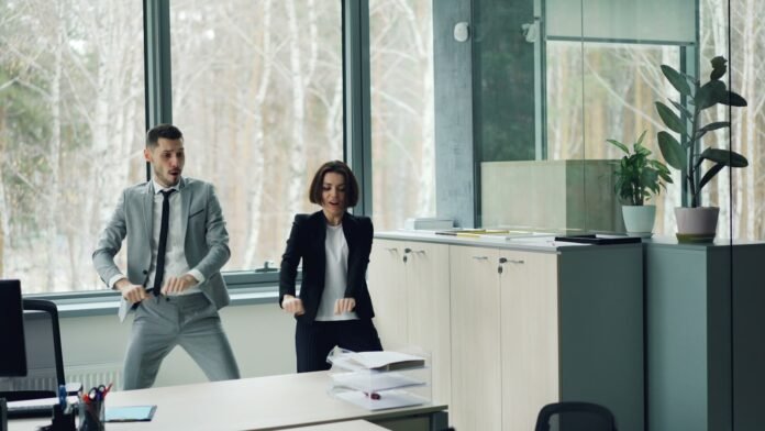 jira-service-management-alternatives-featured Man and woman dancing in an office.