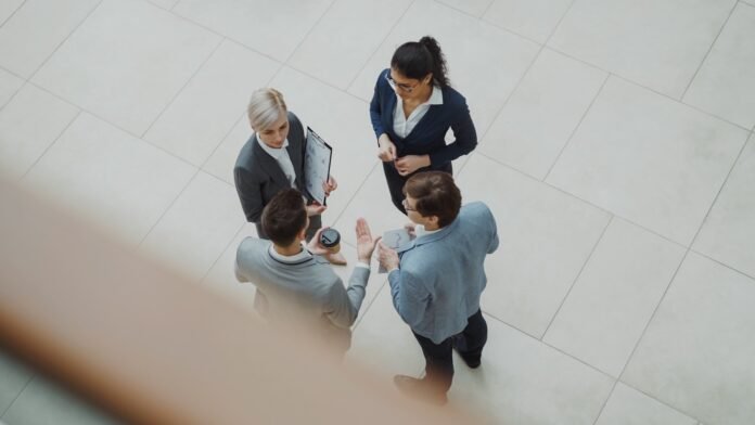 software-audit-preparation-featured Four business people talking in a modern office lobby.