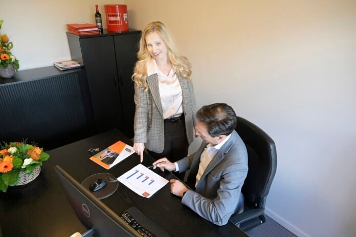 change-management-roi-featured Businesswoman pointing at documents for businessman in office.