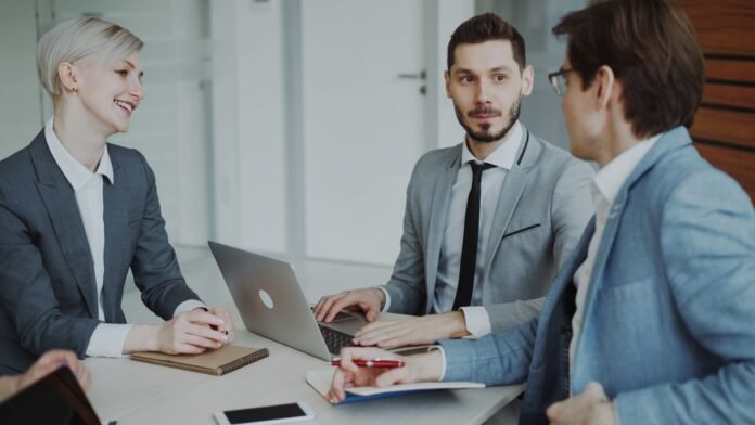 standard-vs-normal-vs-emergency-changes-featured Business professionals in a meeting around a table.